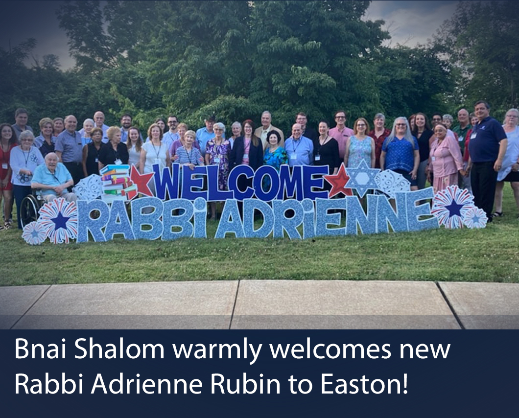 Colorful outdoor sign with congregants surrounding Rabbi Adrienne is pictured